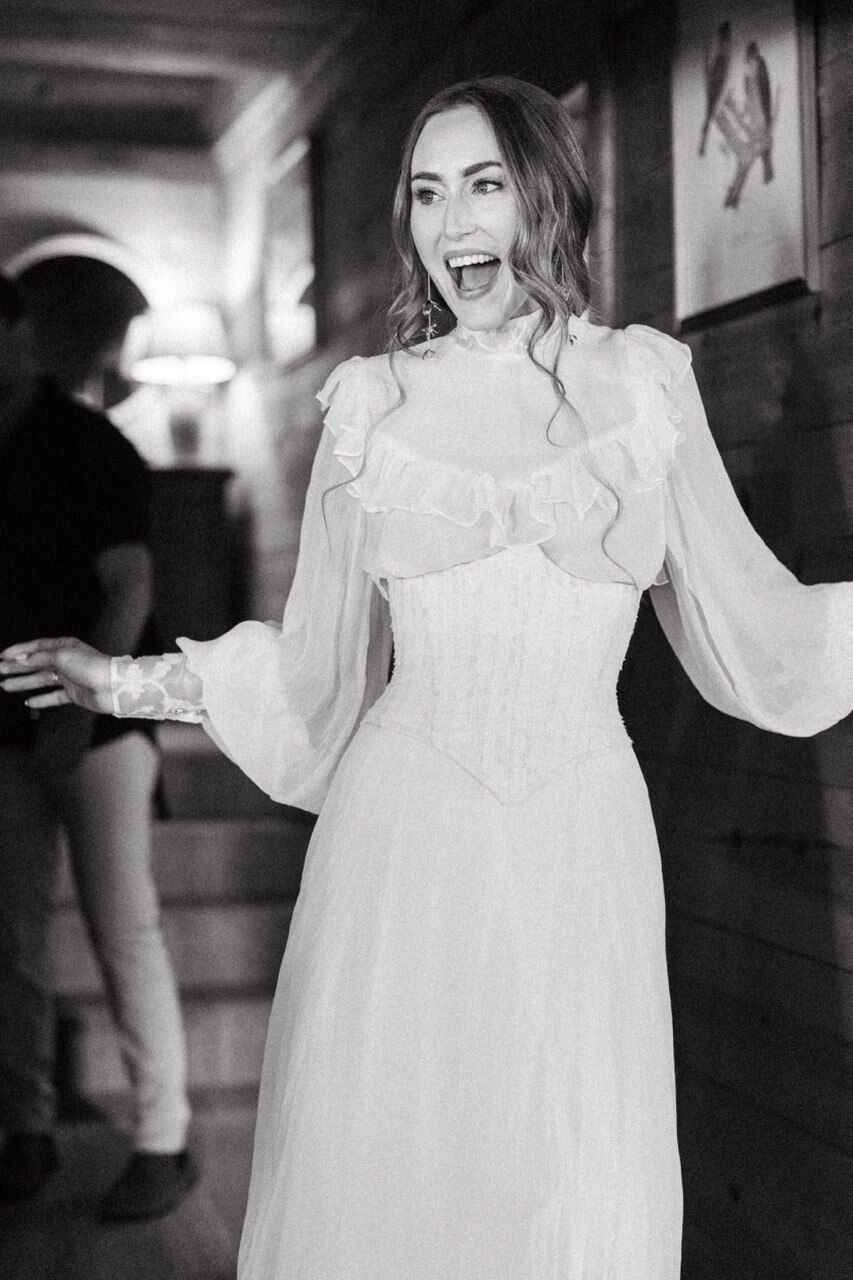 Bride laughing in a custom ruffled high-neck corseted bridal gown — Blár Studio